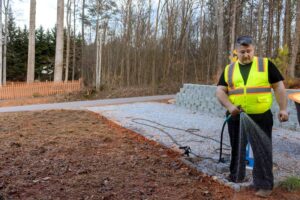 Man waters area of ground where grass seed was sown