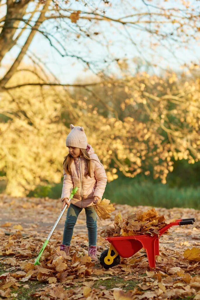 Girl raking up leaves in garden